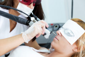 Young beautician removing facial hair with a laser to her client